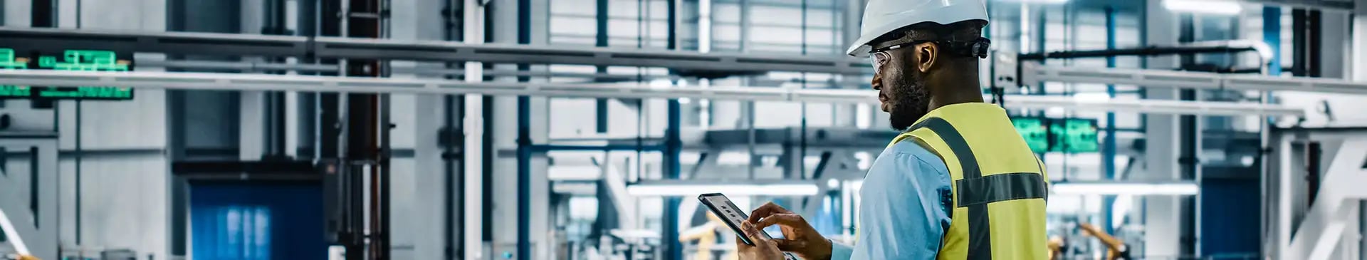 Mann steht mit Tablet in der Produktion